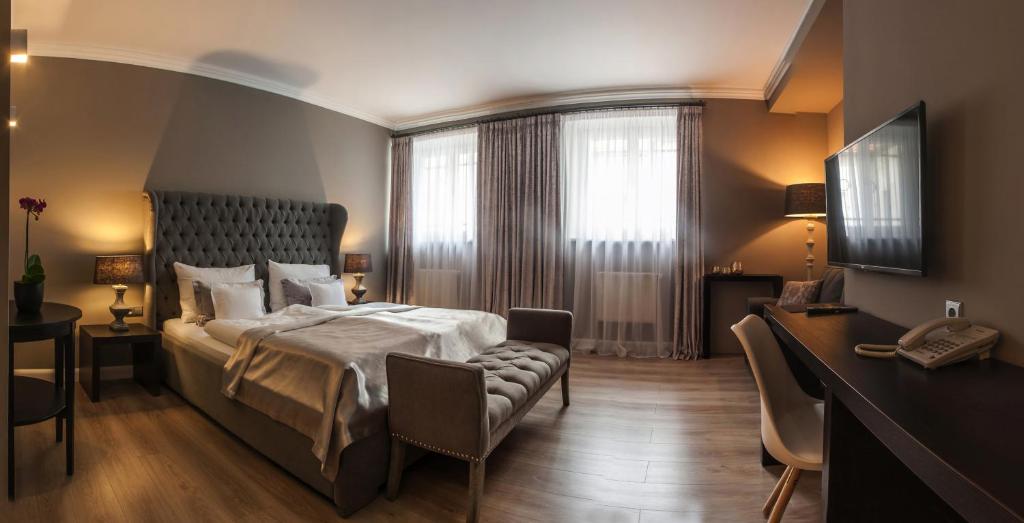 a bedroom with a bed and a desk and a window at Hotel Rango in Plzeň