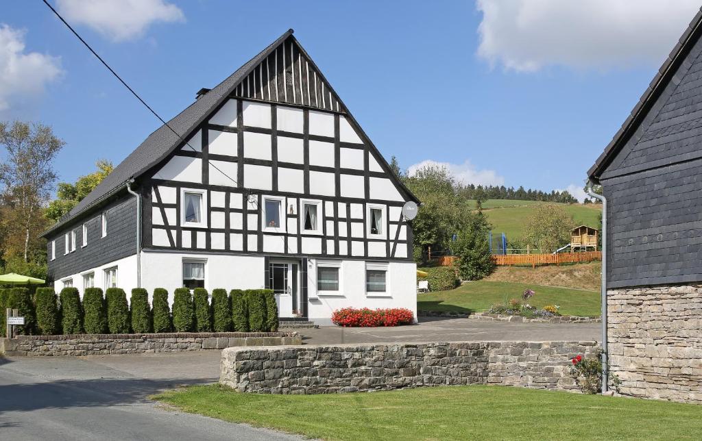 ein schwarzweißes Haus mit einer Steinmauer in der Unterkunft Ferienbauernhof Familie Stratmann in Eslohe