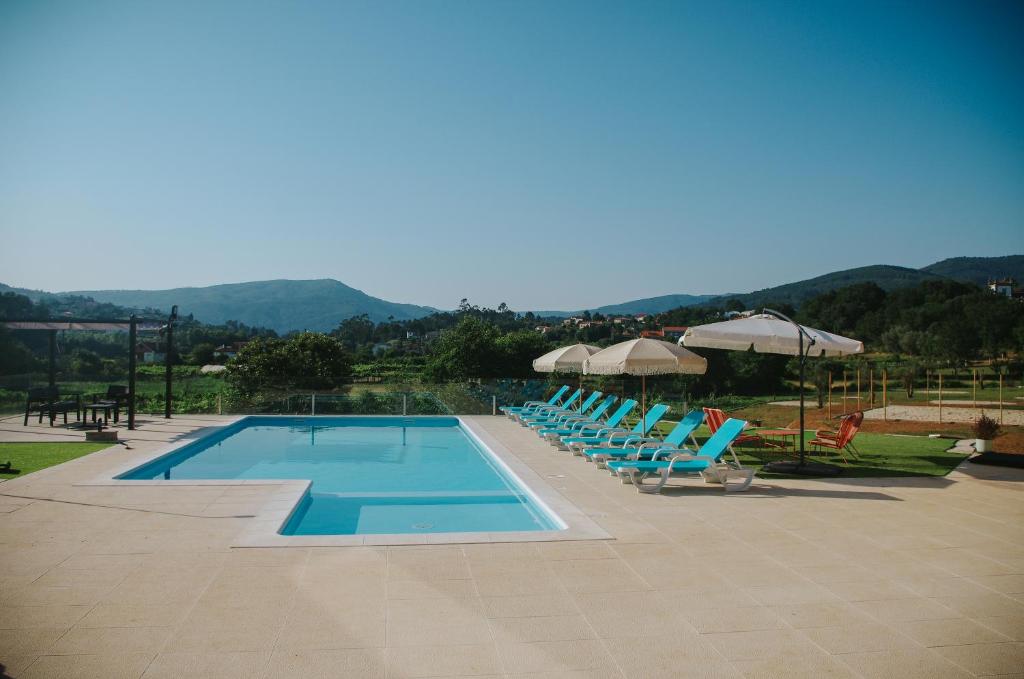 a swimming pool with blue chairs and umbrellas at Sandoco - Golf - Pickleball - Beach Volleyball & Pool - All Exclusive in Ponte de Lima