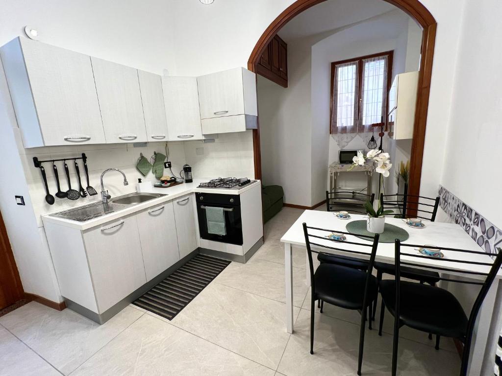 a kitchen with white cabinets and a table with chairs at Porto Vecchio Apartment in Sanremo