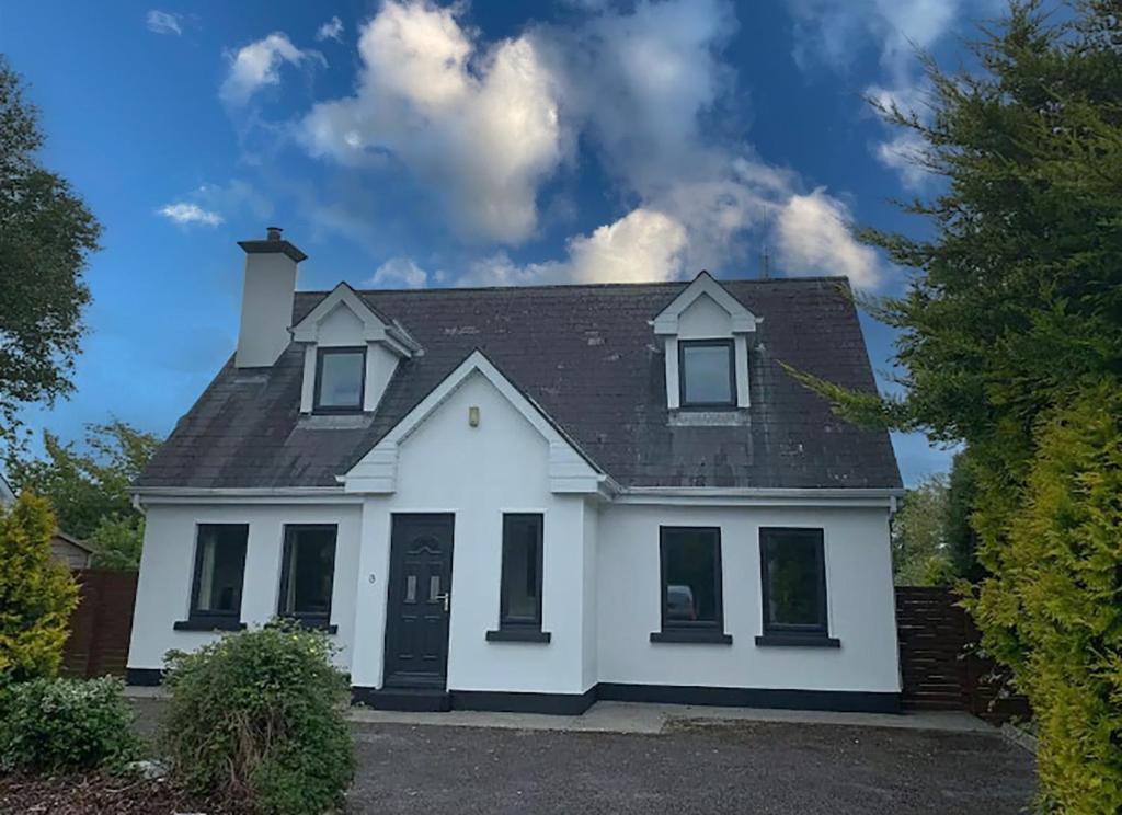 a white house with a black roof at Burren Seaside Lodge by Trident Holiday Homes in Ballyvaughan