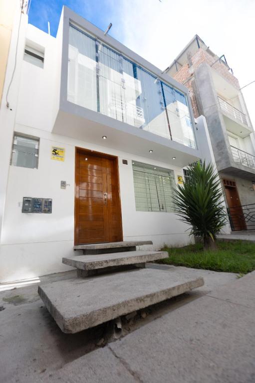 a white house with a wooden door and stairs at Casa completa, 5 dormitorios y jardín in Ayacucho