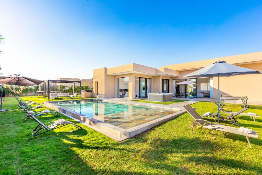 a house with a swimming pool with chairs and an umbrella at Villa Prestige Privée avec Vue Splendide in Marrakesh