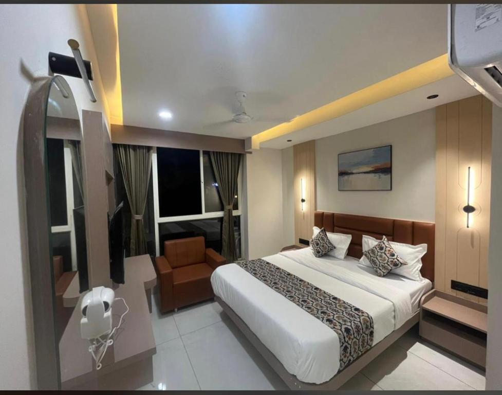 a bedroom with a large bed and a chair in it at Hotel Plus Point in Ahmedabad