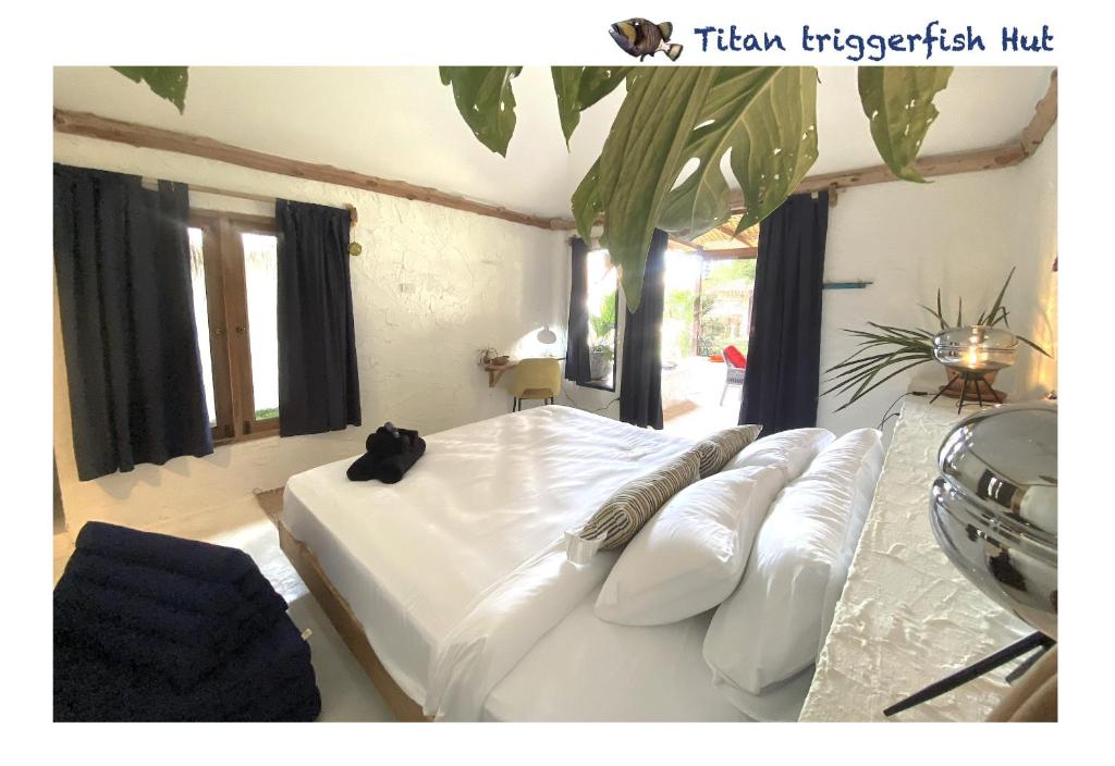 a bedroom with a large white bed with pillows at Triggerfish Hut at Casa Domingo in Ban Thong Phlu