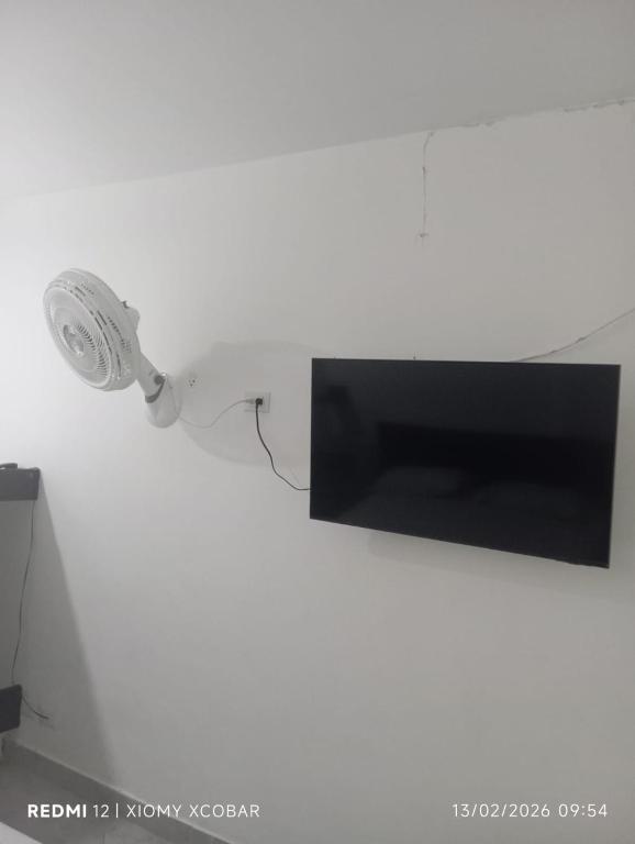 eine an der Wand befestigte Lampe mit einem Fernseher in der Unterkunft Hotel eden centro in Medellín