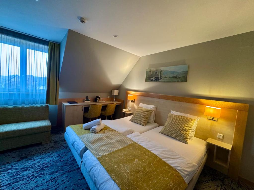 a hotel room with a bed and a couch at Logis Hôtel Restaurant & Spa au Soleil in Wettolsheim
