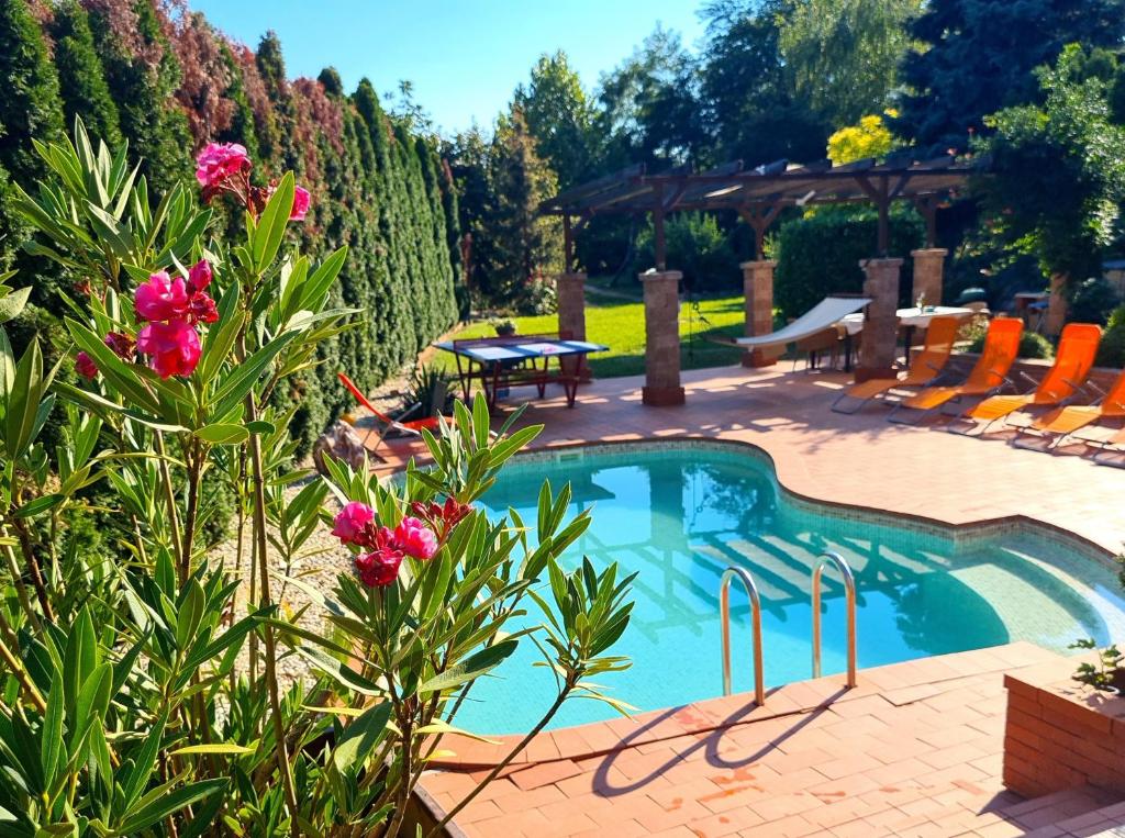 a swimming pool in a yard with chairs and flowers at Relax Holiday House in Balatonrendes