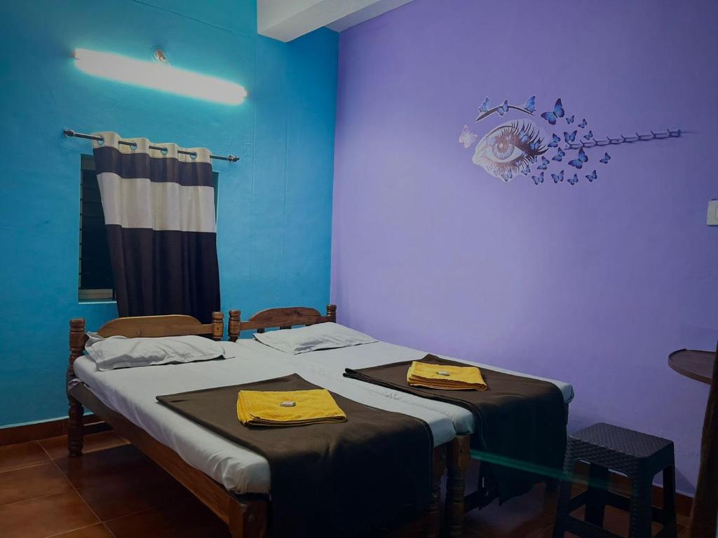 two twin beds in a room with blue walls at Aarvi Residency in Māvalli