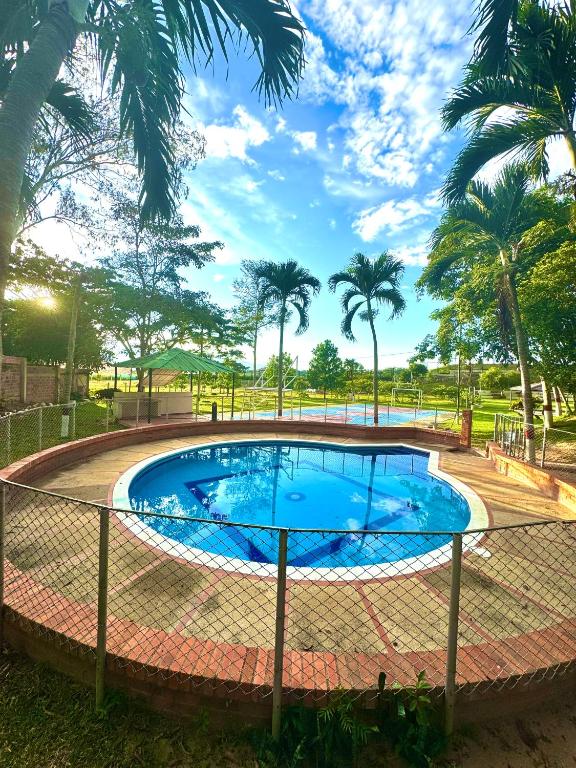 a swimming pool with a fence around it with palm trees at Hacienda Torcoroma in Bucaramanga