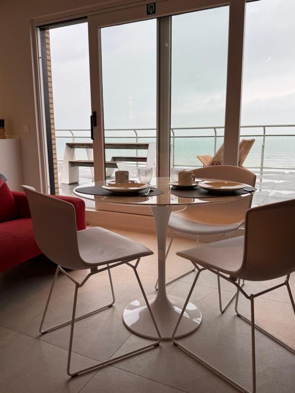 a table and chairs in a room with a view of the ocean at Secret Stay, Wellness Penthouse studio, Privacy, Seaview, Terras, Sauna in Koksijde