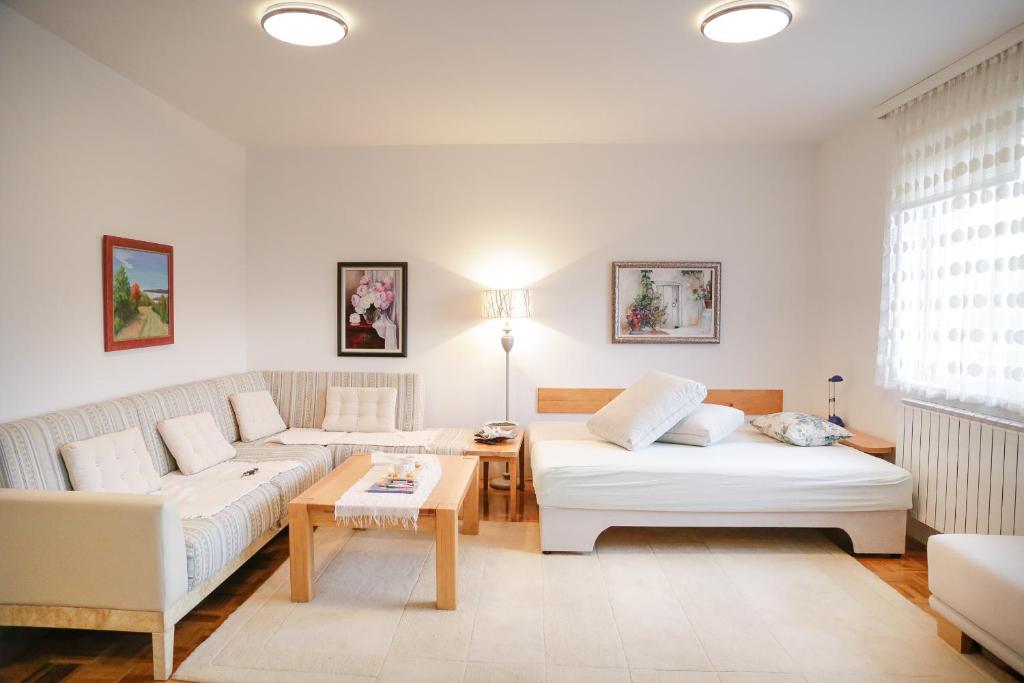 una sala de estar con 2 sofás blancos y una mesa. en Guest Apartment Visoko, en Visoko