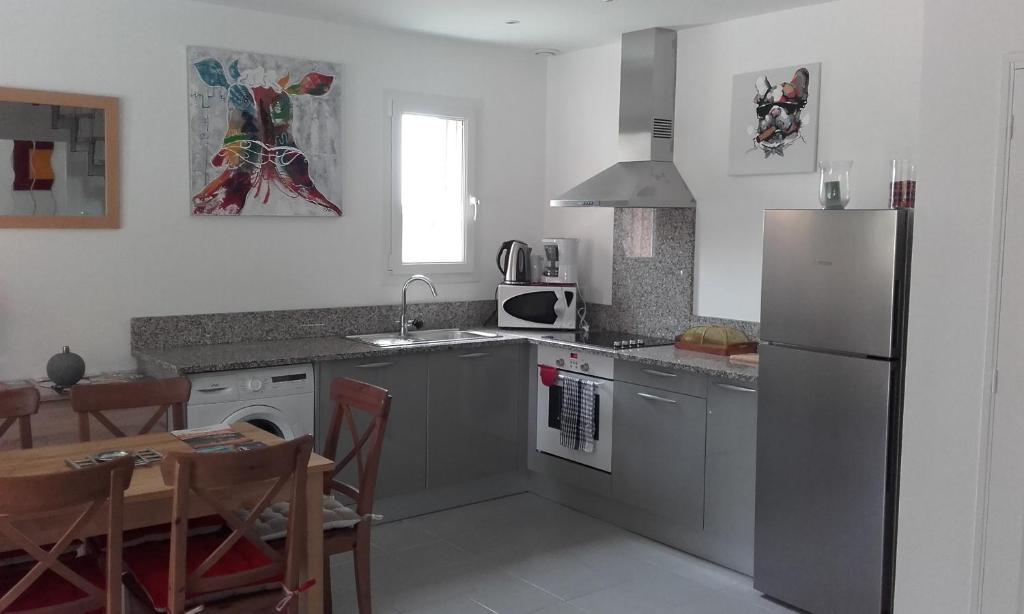 une cuisine avec un réfrigérateur en acier inoxydable et une table dans l'établissement Les jumelles, à Sarlat-la-Canéda