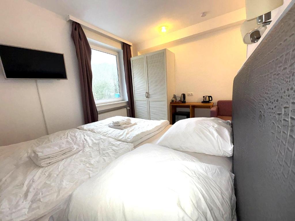 ein Schlafzimmer mit einem Bett mit weißer Bettwäsche und einem Fenster in der Unterkunft M2 Rooms in Lübeck