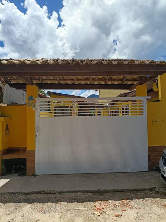 a white garage door with a wooden pergola at Pousada da Tom-Ubatuba Perequê-Açu in Ubatuba