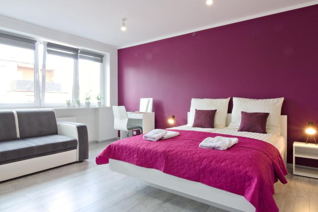 a purple bedroom with a bed and a chair at LC pokoje & apartamenty B52 in Szczecin