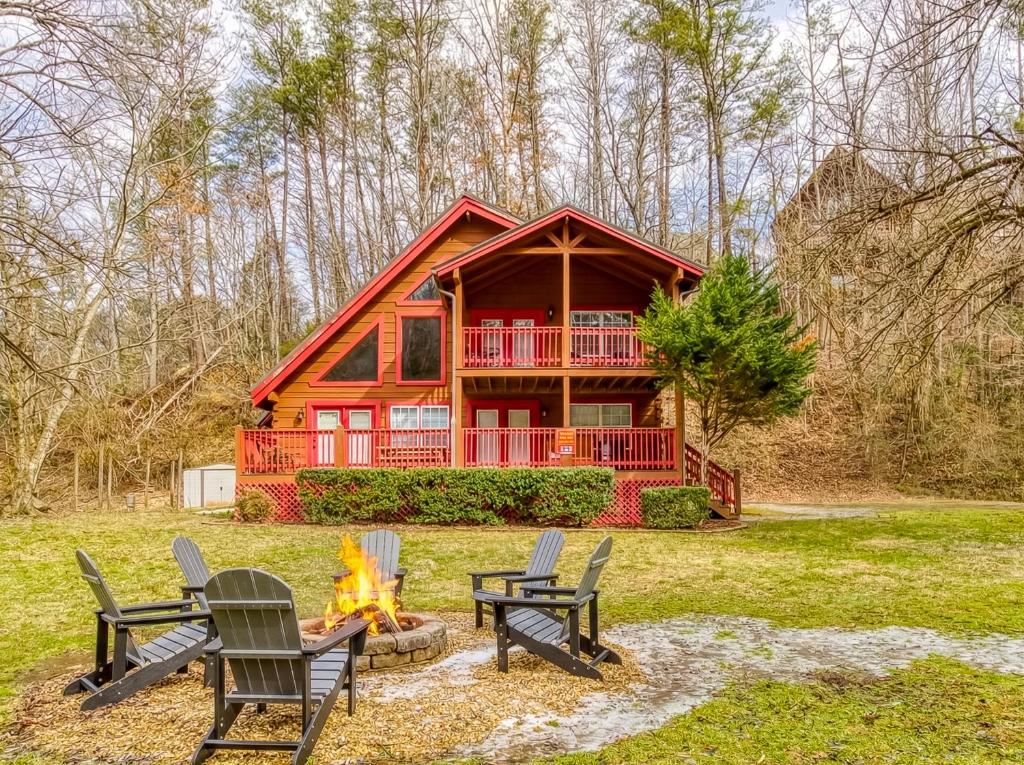a cabin in the woods with chairs and a fire at Ole Red in Gatlinburg