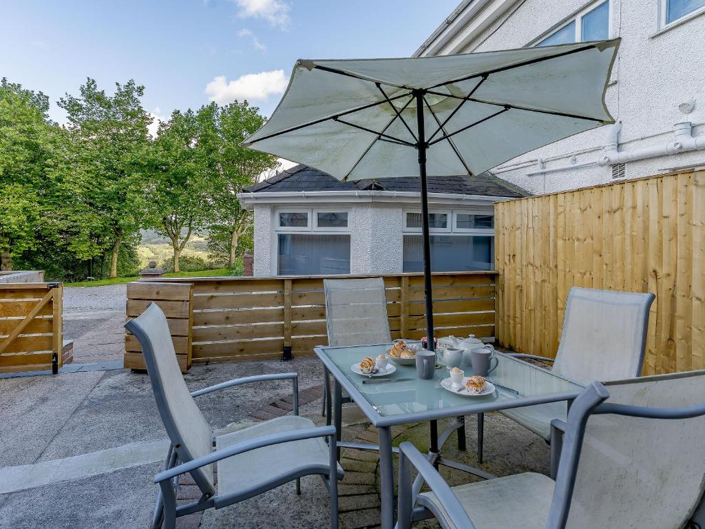 a table and chairs with an umbrella on a patio at The Cottage-Uk32854 in Neath