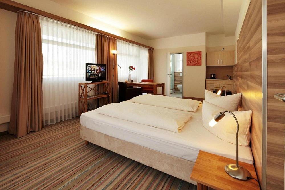 a hotel room with a large bed and a lamp at Petul Apart Hotel City in Essen