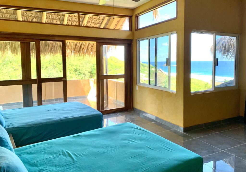 a room with two beds and a view of the ocean at Departamento con vista al mar, Wifi Starlink y AC en Playa San Agustinillo in San Agustinillo