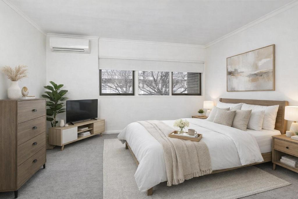 a white bedroom with a bed and a television at Modern 2BR Apartment North Adelaide in North Adelaide