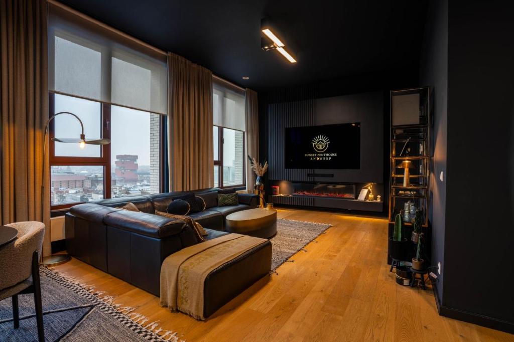 a living room with a couch and a tv at Sunset Penthouse Antwerp in Antwerp