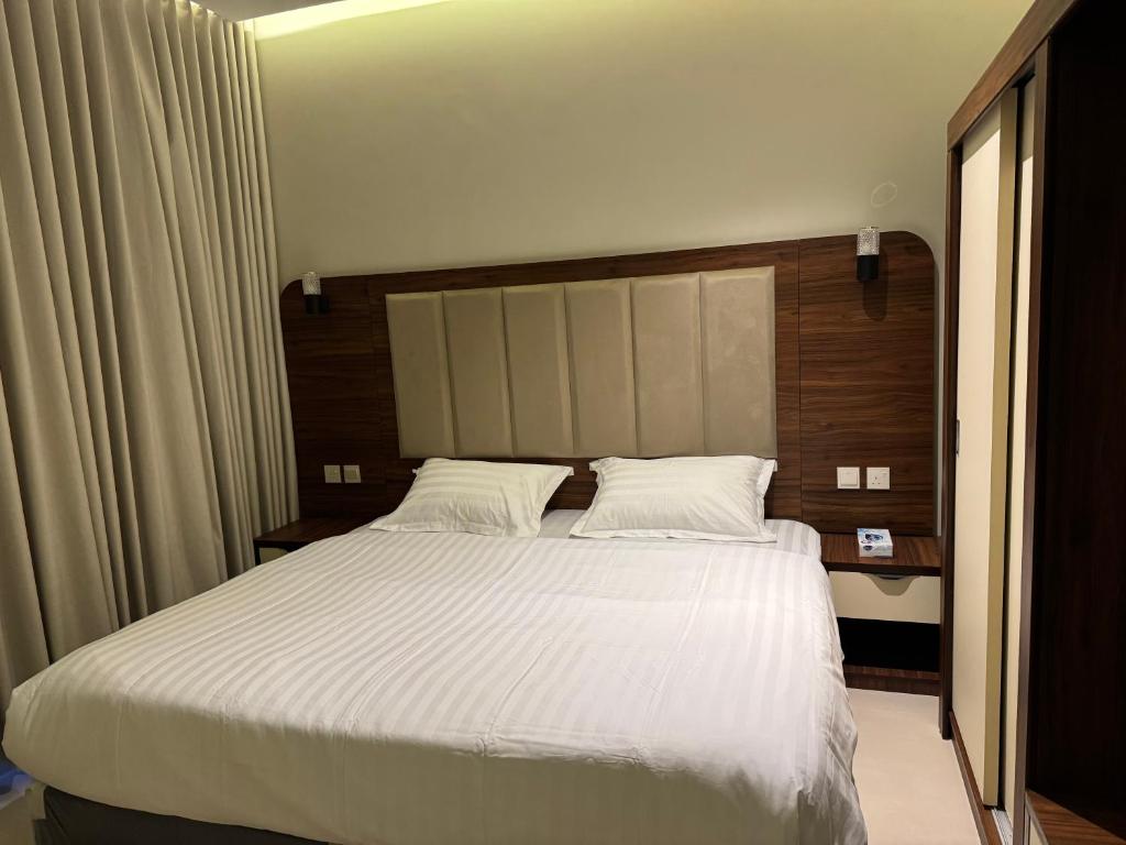 a bedroom with a large bed with white sheets at Milano Hotel in Al-ʿUla