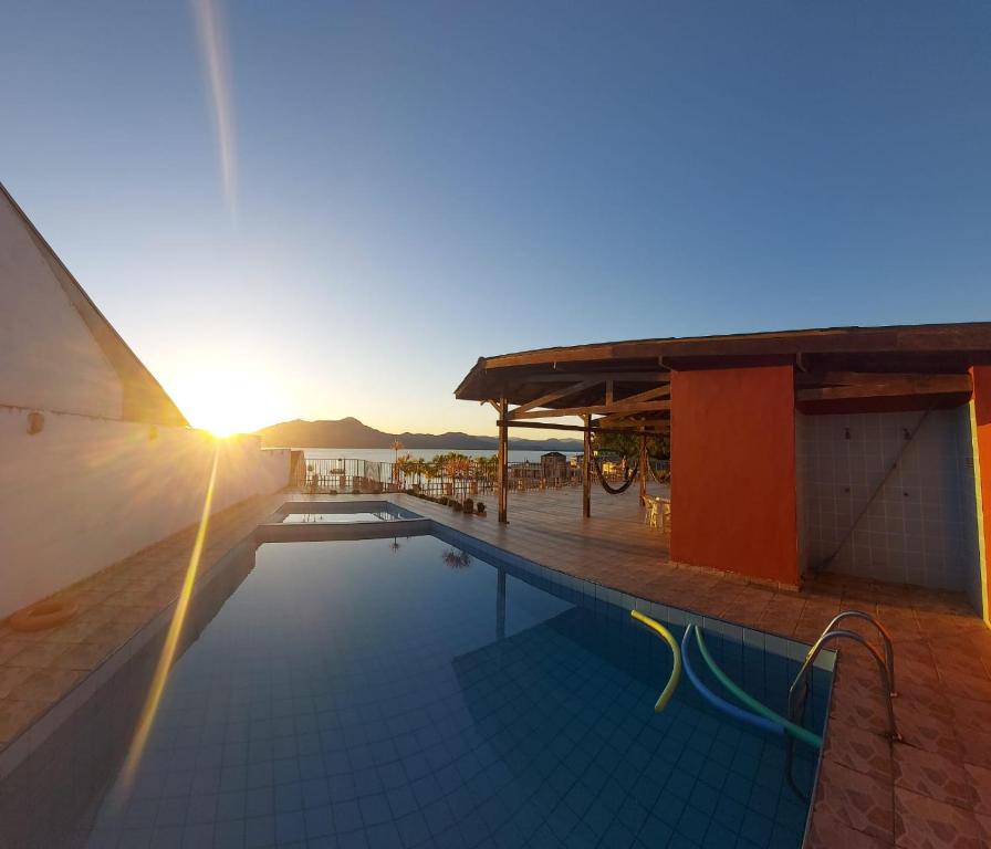 a swimming pool with the sun setting in the background at Hotel Guarakessaba in Guaraqueçaba