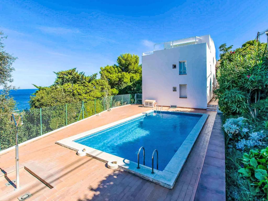 a swimming pool in front of a house with the ocean at Apartment Salina by Interhome in Llança