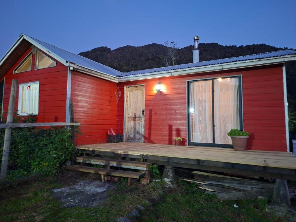 a red house with a wooden deck in front of it at Cabaña Hornohuinco in Llanquihue