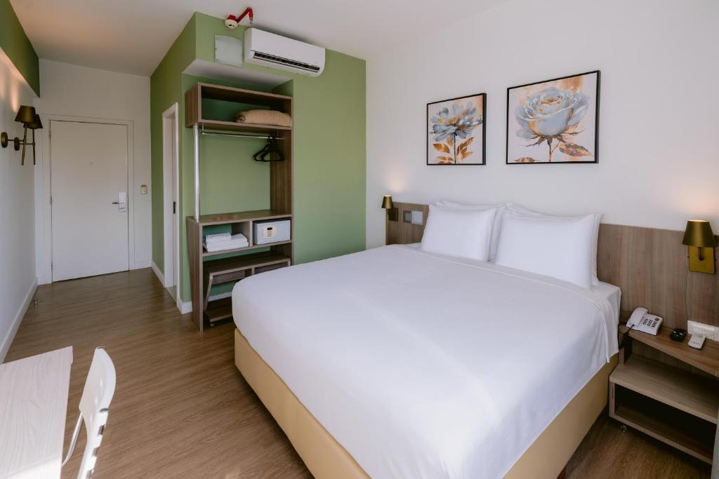 a bedroom with a white bed and a green wall at Slim Hotel Cuiabá Aeroporto in Cuiabá