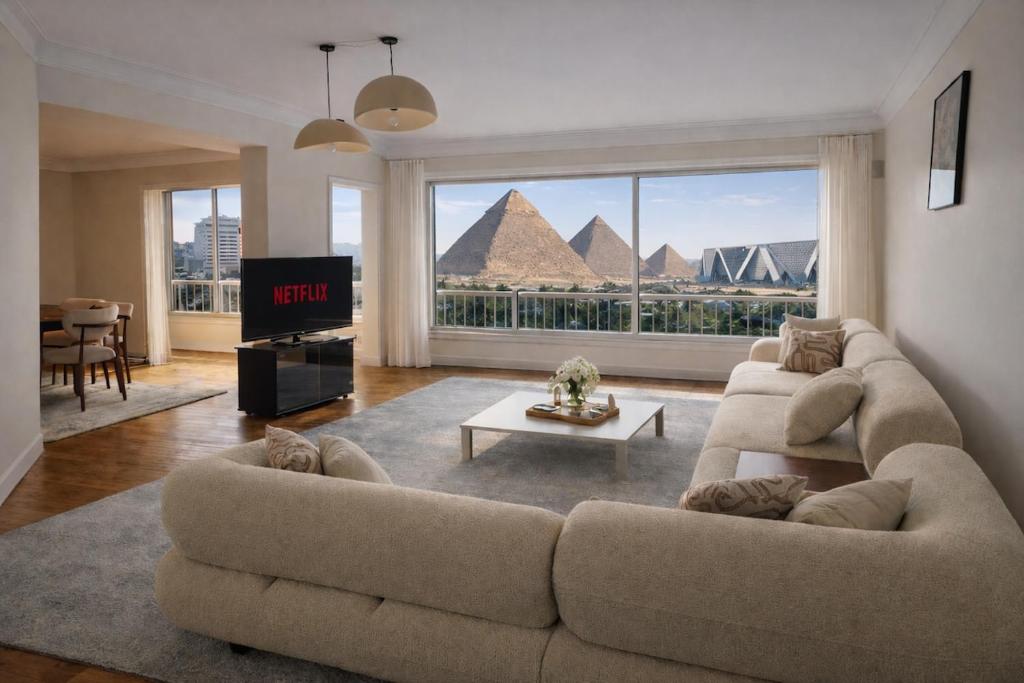 a living room with a couch and a view of pyramids at 3 Pyramids Grand Egyptian Museum View in Cairo