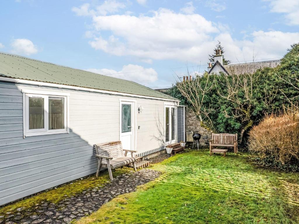 a small white house with two benches in the yard at Chalet The Chalet by Interhome in Fort Augustus