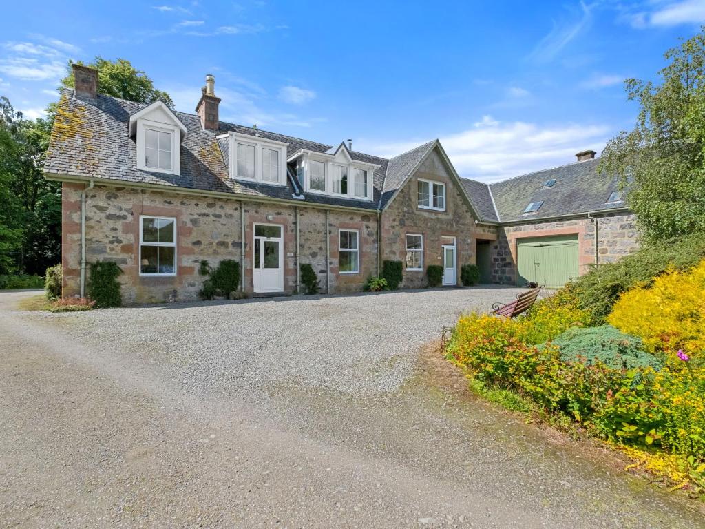 a large stone house with a gravel driveway at Apartment Old Stable on Aigas Golf Course by Interhome in Beauly