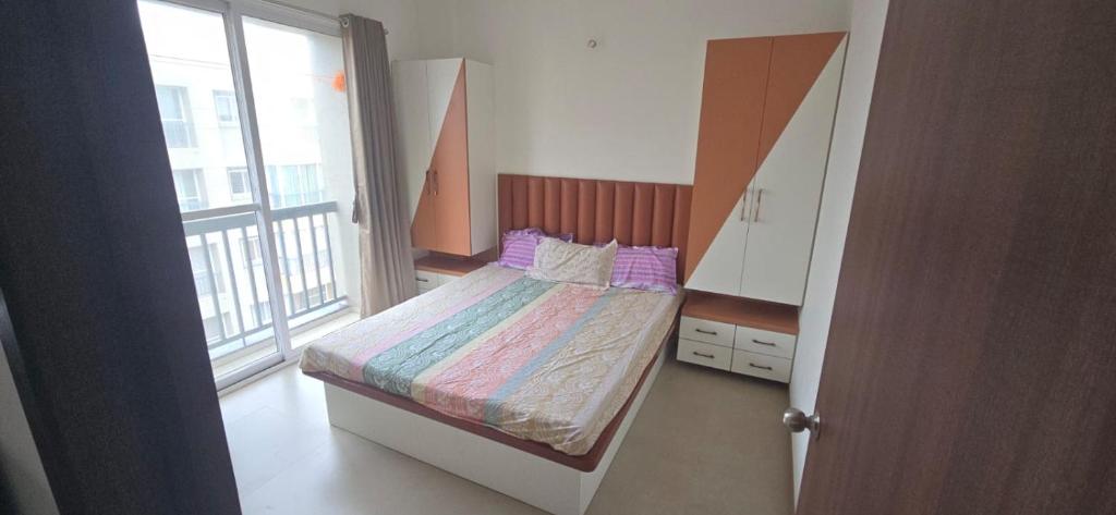 a small bedroom with a bed and a large window at Apartment in Igatpuri! in Igatpuri