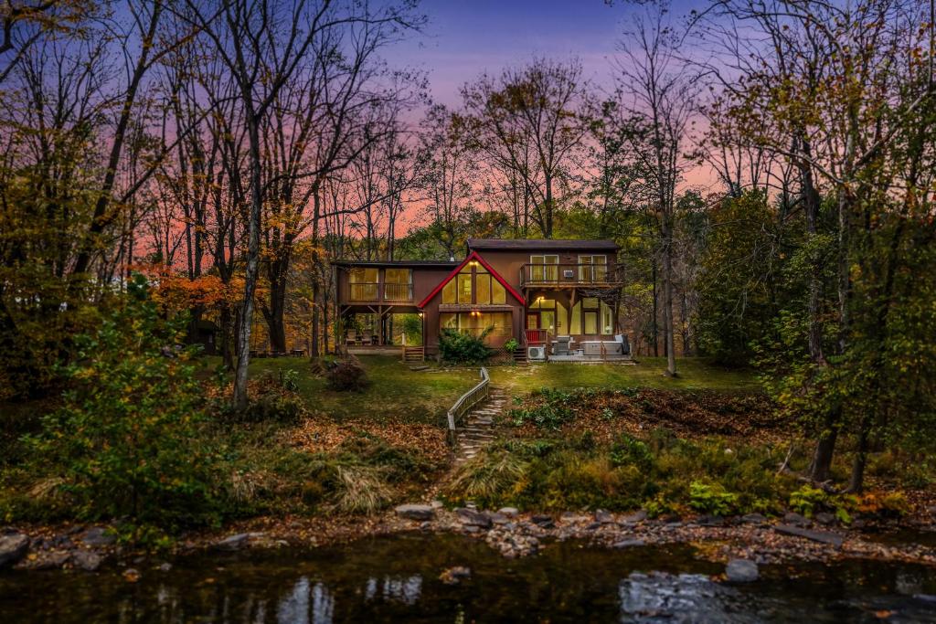 a house in the middle of a forest at River Time Cabin - Riverfront, Hot Tub, Screen Porch, Fishing, Games, View, 3 King Beds in Berkeley Springs