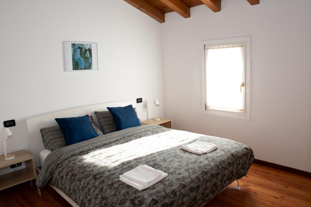 a bedroom with a bed with blue pillows and a window at A casa di Giò in Vittorio Veneto