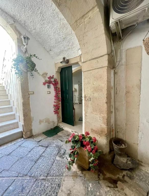 an entrance to an old building with flowers on the floor at Donna Sicilia Ortigia in Syracuse