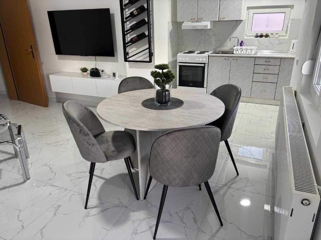 a kitchen with a table with chairs and a tv at Apartman Rose in Čapljina