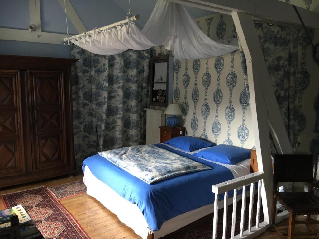 - une chambre avec un lit à baldaquin et des draps bleus dans l'établissement Le Prieuré Boutefol, à Surville