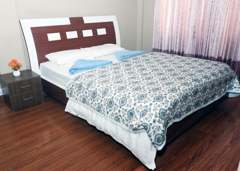 a bedroom with a bed with a comforter on it at Pepa's villa and homestay in Khadkagaon