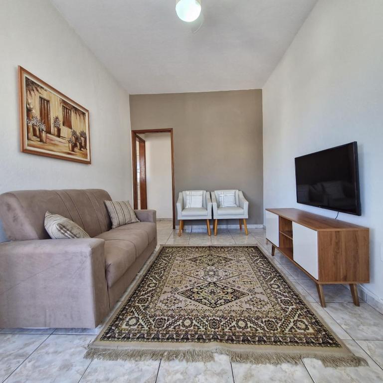 a living room with a couch and a flat screen tv at Refúgio Aura,casa com suíte, wi-fi, garagem e churrasqueira in Aparecida