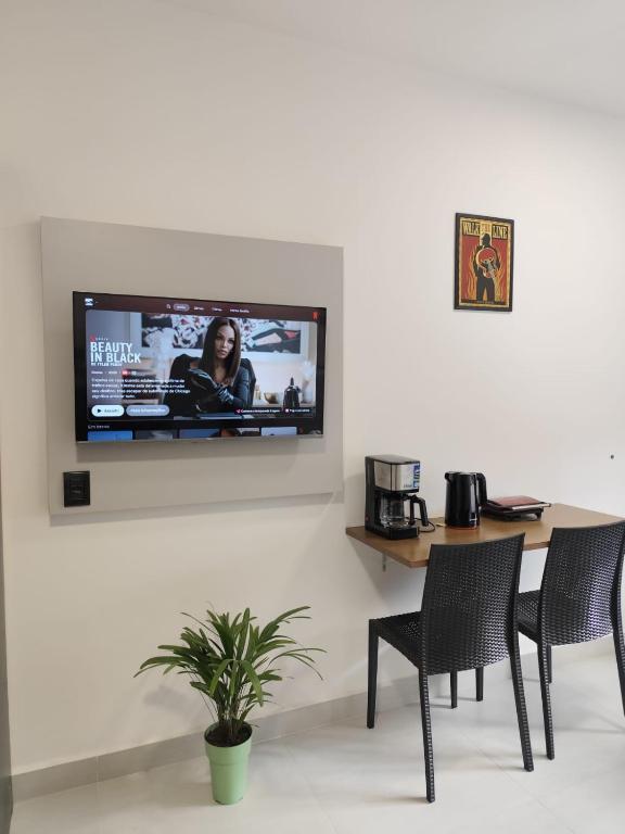 a television on a wall with a table and chairs at Studio com Ar condicionado, Boa Localização, Internet Rápida 2 in Joinville