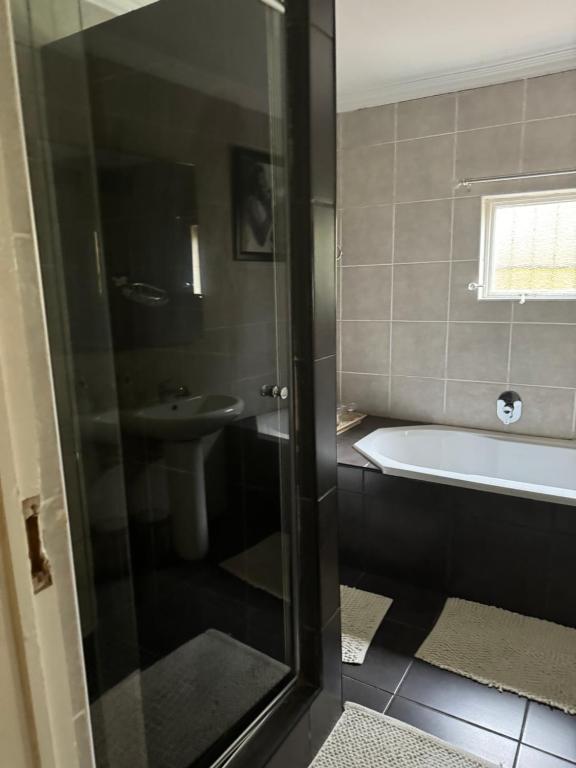 a bathroom with a tub and a toilet and a sink at Virginia Town House in Mthatha