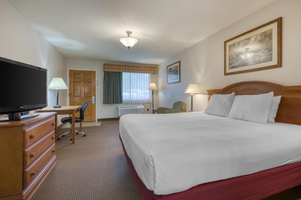 a hotel room with a bed and a flat screen tv at SureStay Hotel by Best Western Leesville in Leesville