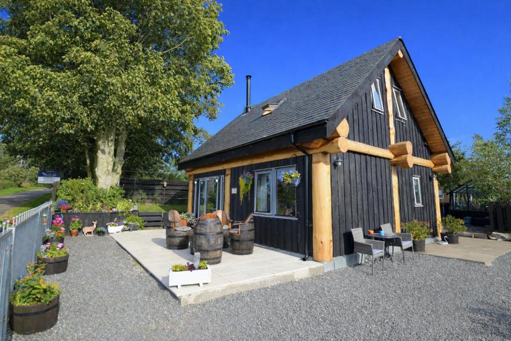 a tiny house with a black roof at Rowanlea Lodge Hot Tub Secure Garden Pub 5 min walk in Laurencekirk