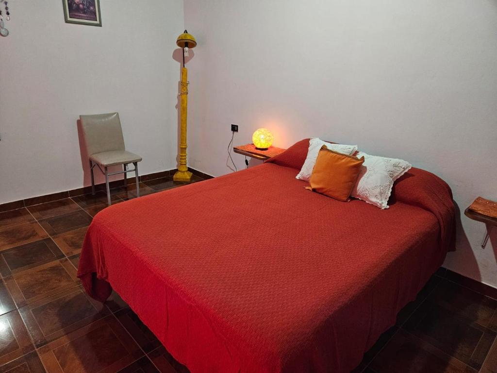 a bedroom with a red bed with a lamp and a chair at Posada Oporto in La Rioja