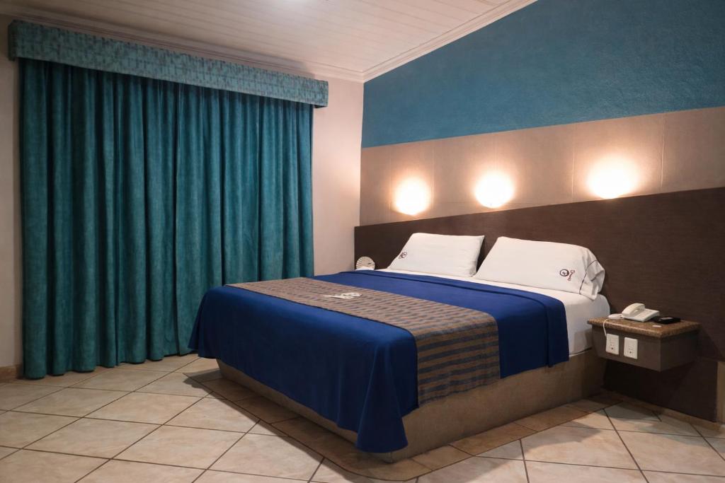 a bedroom with a large bed with blue curtains at Autohotel Punto de Descanso Cordoba in Córdoba