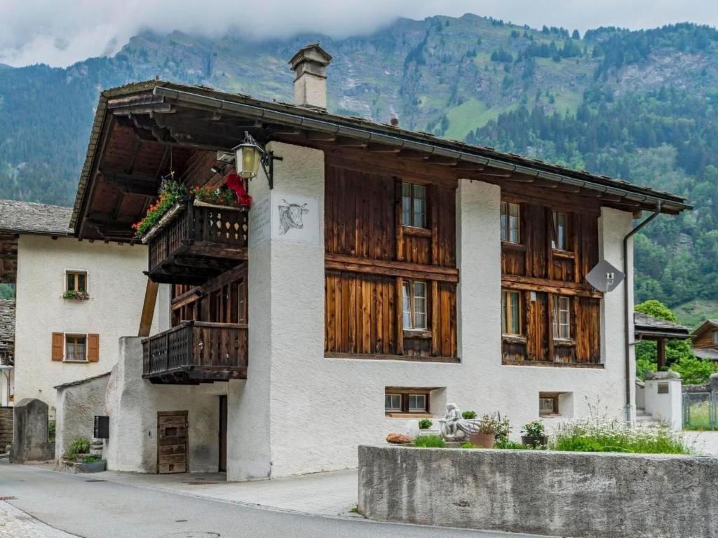 a building with wooden doors and windows with mountains in the background at Apartment Wohnung Muntegn by Interhome in Vicosoprano