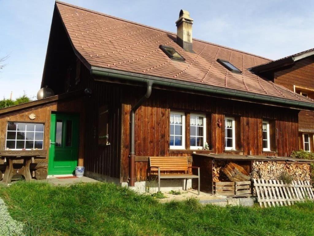 a wooden house with a green door and a bench at Apartment Haggen by Interhome in Oberegg